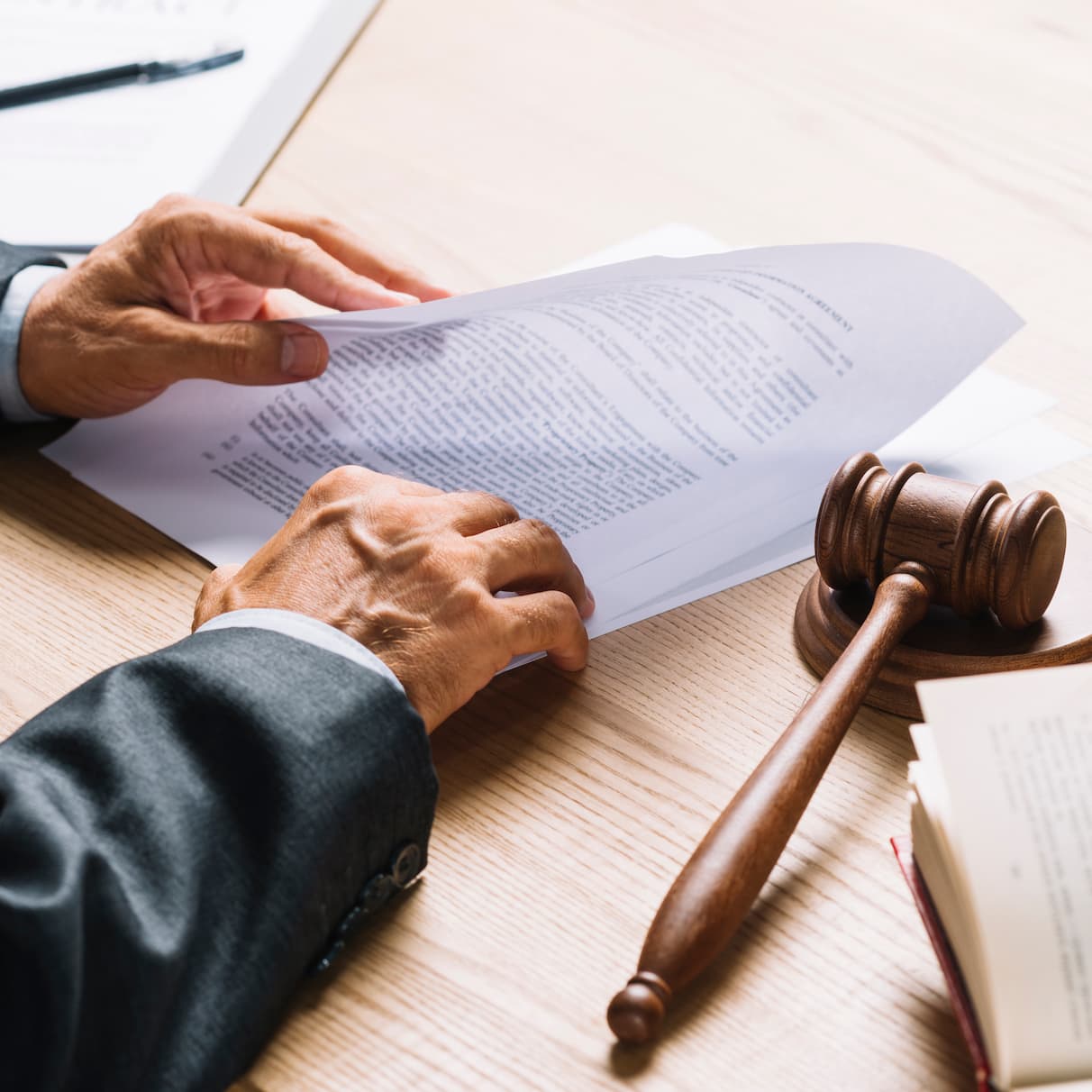 lawyer-s-hand-holding-document-with-gavel-mallet-wooden-desk(1)